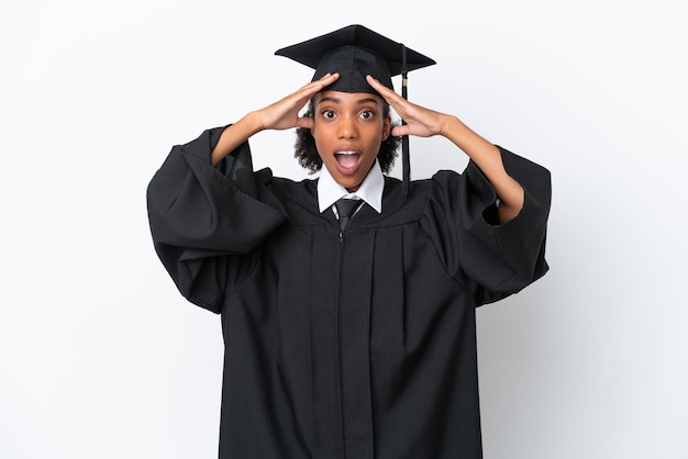 Mulher afro-americana jovem graduada em universidade isolada em fundo branco com expressão de surpresa