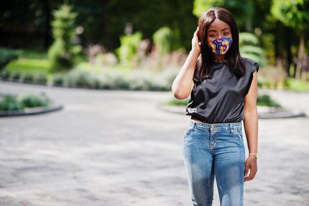 Mulher afro-americana na moda, use máscara facial feita à mão posando ao ar livre. Nova vida normal.