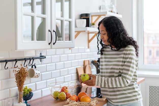 Mulher afro-americana olhando maçãs coloridas comprando lanche de dieta de produtos vegetarianos saudáveis