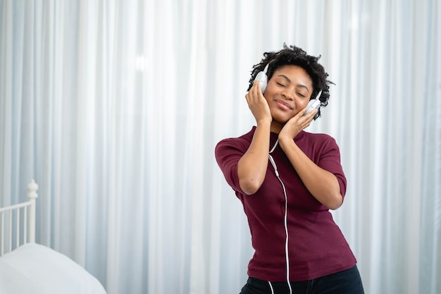 Mulher afro-americana ouvindo música com fones de ouvido na sala de estar