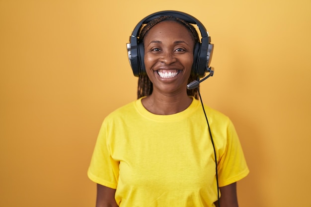 Mulher afro-americana ouvindo música usando fones de ouvido com um sorriso feliz e legal no rosto. pessoa sortuda.