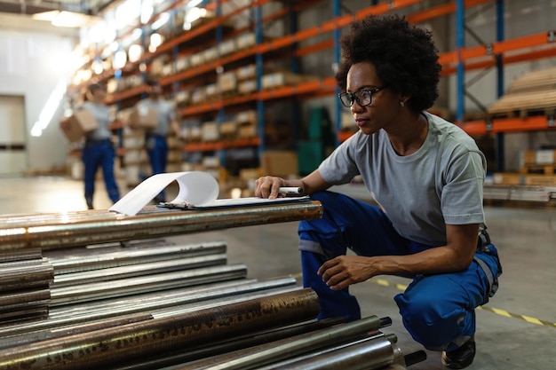Mulher afro-americana passando pela lista de verificação enquanto trabalhava no armazém de distribuição