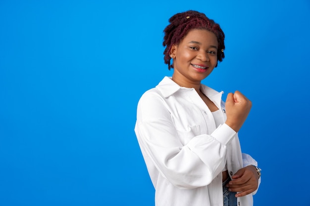 Mulher afro-americana se sentindo forte, mostrando o punho contra um fundo azul
