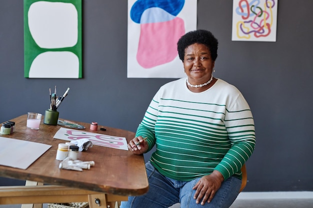 Mulher afro-americana sênior sorridente em roupas casuais sentada no estúdio