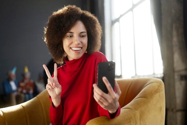 Mulher afro-americana sorridente segurando comunicação de telefone móvel on-line mostrando sinal de paz