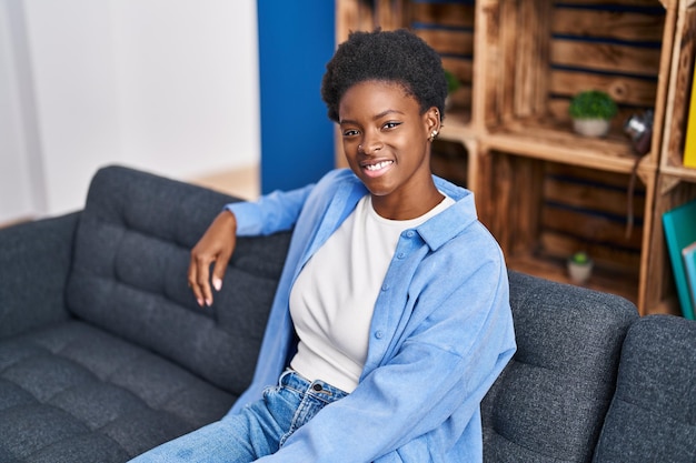 Mulher afro-americana sorrindo confiante sentada no sofá em casa