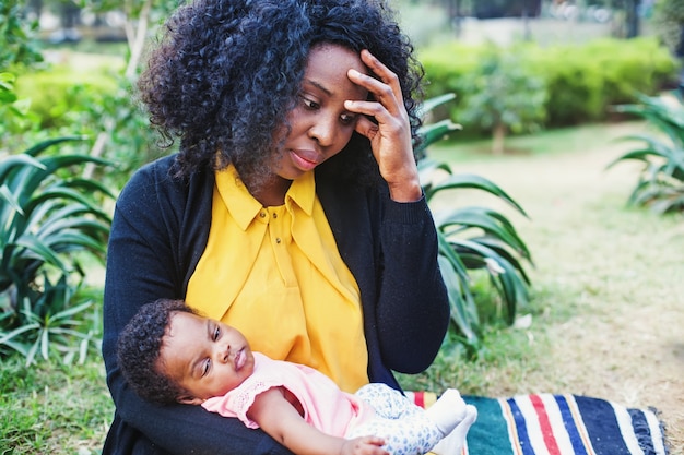 Mulher afro-americana triste segurando seu filho e pensando