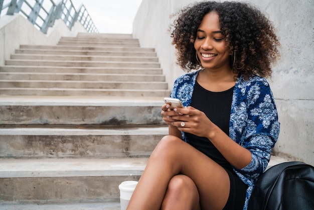 Mulher afro-americana, usando seu telefone celular.