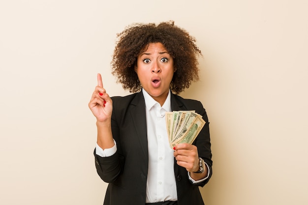 Mulher afro-americano nova que guarda os dólares que têm alguma grande ideia, conceito da faculdade criadora.