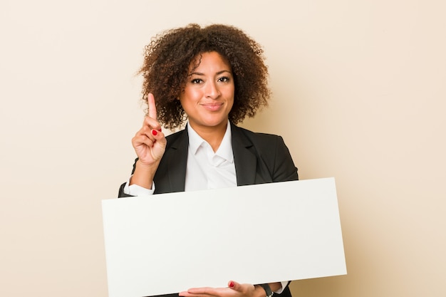 Mulher afro-americano nova que guarda um cartaz que mostra o número um com dedo.