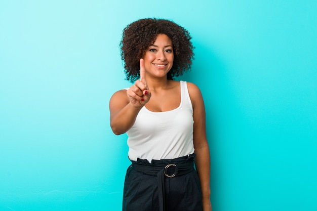 Mulher afro-americano nova que mostra o número um com dedo.