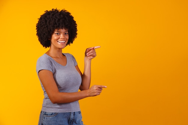 Foto mulher afro apontando em amarelo com espaço para o texto