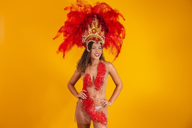 Mulher afro brasileira posando com fantasia de samba sobre fundo amarelo com espaço livre. traje de samba vestido de brasileiro.