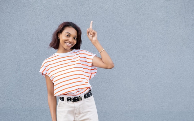 Mulher afro chocada espantada mostra boa oferta de venda ou acordo prende a respiração demonstra espaço de cópia vazio para texto promocional surpreso por grandes descontos isolados sobre fundo azul