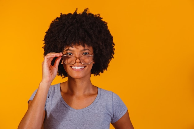 Mulher afro de óculos sorrindo para a câmera