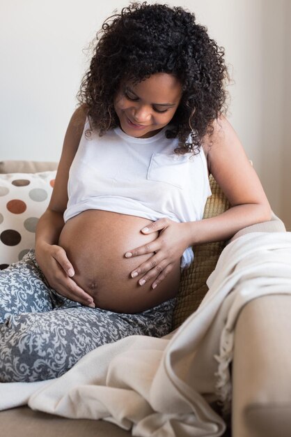 Mulher afro feliz mostrando sua barriga de grávida