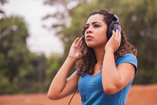 Mulher afro feliz ouvindo música no fone de ouvido dela.