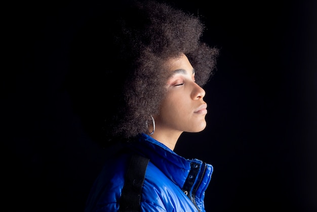 Mulher afro-mista posando em fundo escuro, roupas urbanas, hip hop, estúdio de música