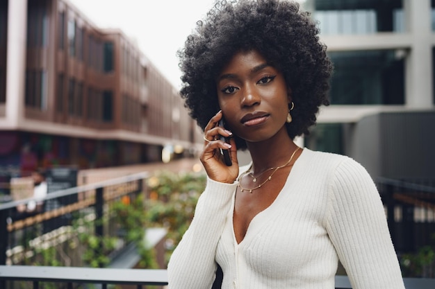 Mulher afro negra falando no celular na cidade