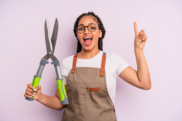 Mulher afro negra se sentindo um gênio feliz e animado depois de realizar uma ideia. conceito de jardineiro ou agricultor