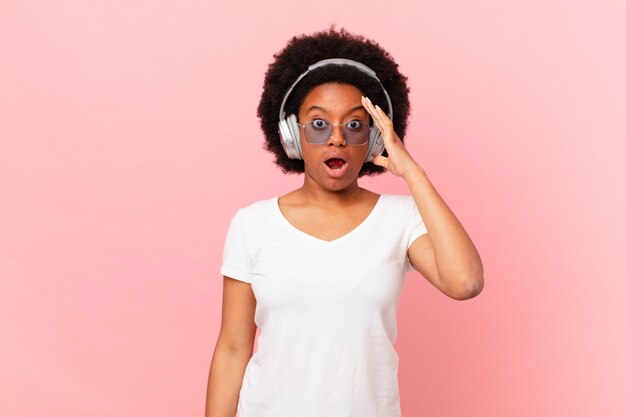 Mulher afro parecendo feliz, espantada e surpresa, sorrindo e percebendo uma boa notícia incrível