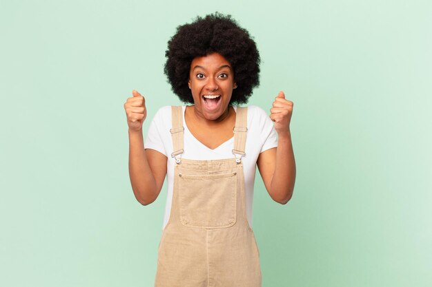 Mulher afro se sentindo chocada, animada e feliz, rindo e comemorando o sucesso, dizendo uau! conceito de chef