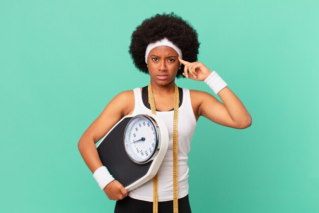 Mulher afro se sentindo confusa e perplexa, mostrando que você é maluca