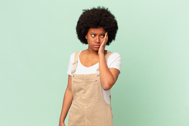 Mulher afro se sentindo entediada, frustrada e com sono depois de uma tarefa cansativa, enfadonha e tediosa, segurando o rosto com a mão do conceito do chef