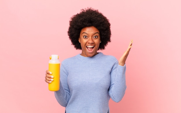 Mulher afro se sentindo feliz, excitada, surpresa ou chocada, sorrindo e atônita com algo inacreditável. conceito smoothy