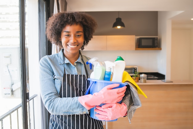 Foto mulher afro segurando um balde com produtos de limpeza