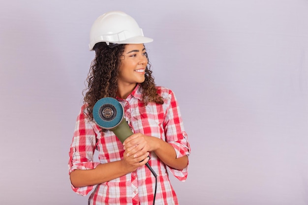 Mulher afro segurando uma lixadeira elétrica. conceito de material de construção