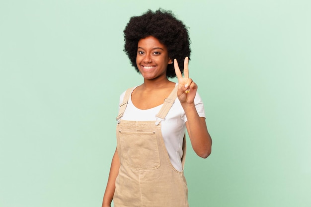 Mulher afro sorrindo e parecendo amigável, mostrando o número dois ou o segundo com a mão para a frente, conceito do chef em contagem regressiva