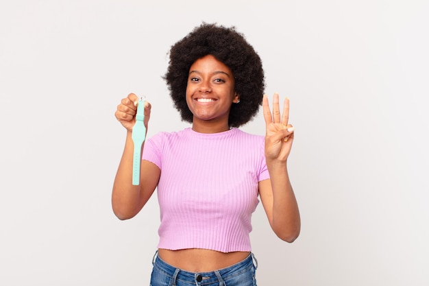 mulher afro sorrindo e parecendo amigável, mostrando o número três ou terceiro com a mão para a frente, conceito de relógio em contagem regressiva