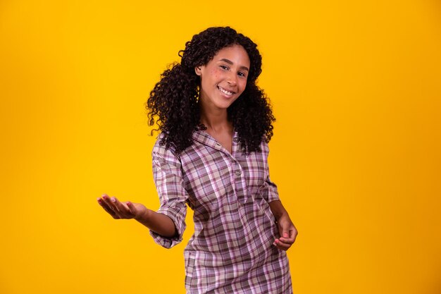 Mulher afro vestida com roupa de festa junina apontando para o lado espaço livre para texto