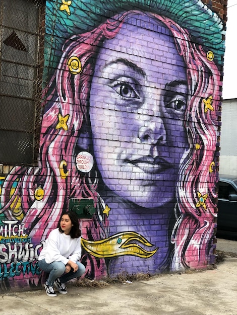 Mulher agachada contra graffiti na parede
