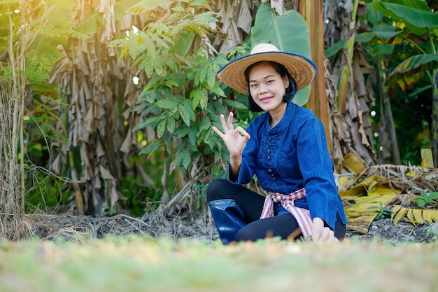 Mulher agricultora asiática sentada e sorriso de mão bem na fazenda