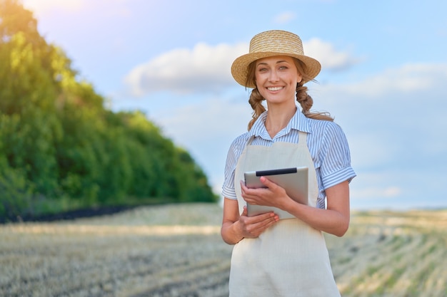 Mulher agricultora chapéu de palha agricultura inteligente em pé terra cultivada sorrindo usando tablet digital mulher especialista em agrônoma pesquisa monitoramento análise de dados agronegócio