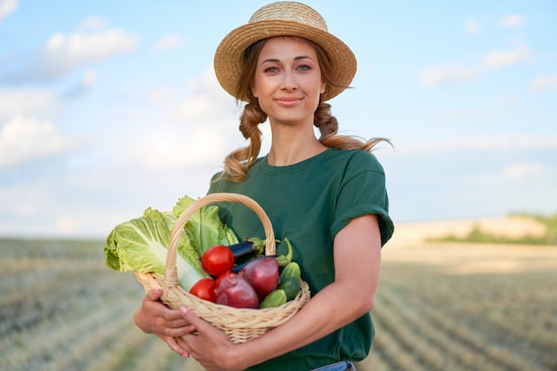 Mulher agricultora, chapéu de palha, avental em pé, fazenda, sorrindo