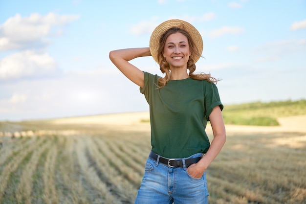 Foto mulher agricultora com chapéu de palha em pé e sorrindo