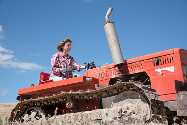 Mulher agricultora dirigindo um trator no campo