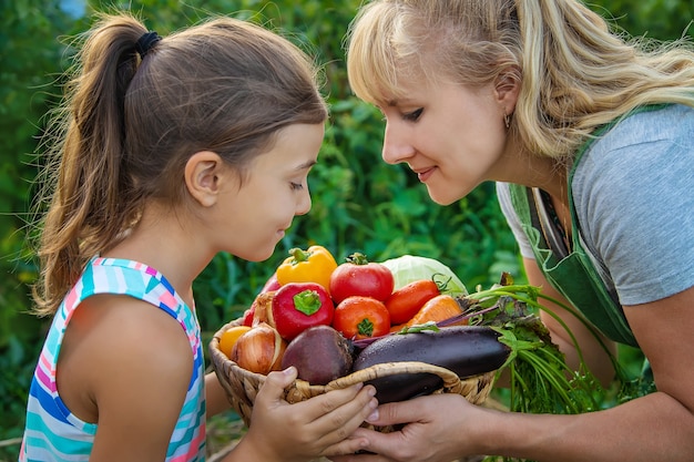 Mulher agricultora e criança no jardim com uma colheita de legumes. foco seletivo. criança.