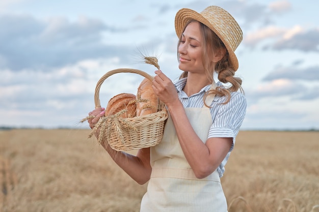 Mulher agricultora em pé campo agrícola de trigo mulher padeiro segurando uma cesta de vime produto de pão