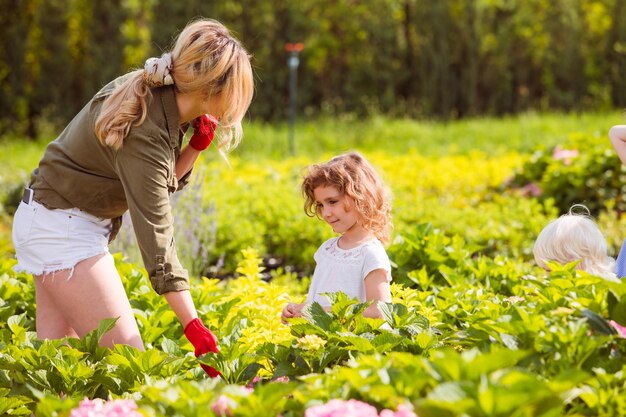 Mulher agricultora mostra à menina como escolher flores de hortênsia
