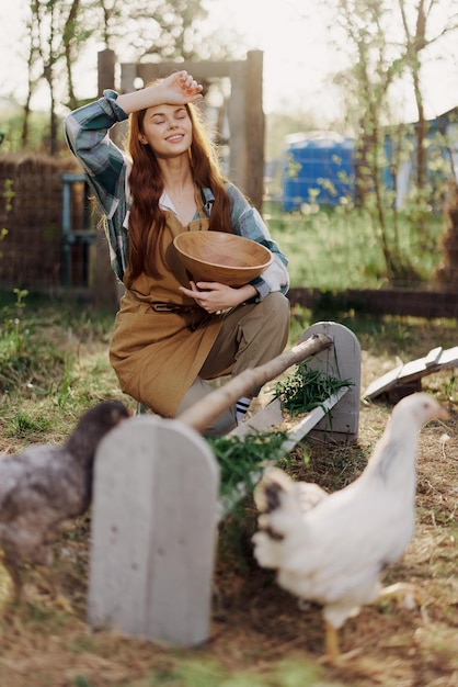 Mulher agricultora sorri alimenta galinhas com alimentos orgânicos para a saúde das aves e bons ovos e cuida do meio ambiente