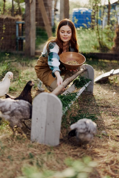Mulher agricultora sorri alimenta pássaros galinhas comida orgânica para a saúde das aves e bons ovos e cuida do meio ambiente luz do sol
