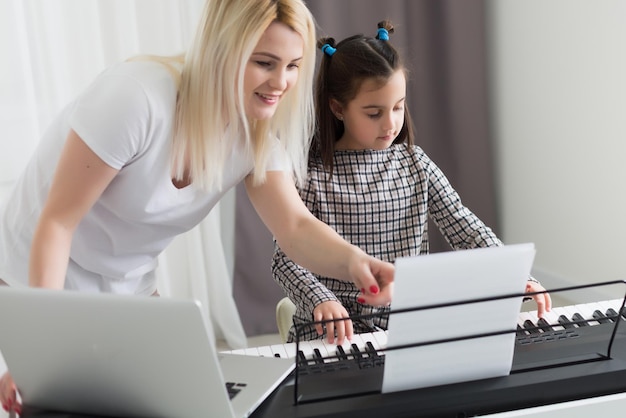 Mulher ajudando sua filha a tocar piano, o corpo e os botões do piano foram modificados digitalmente
