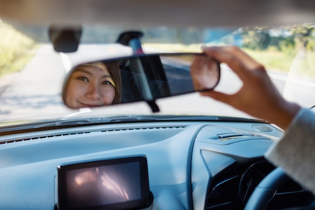 Mulher ajustando um espelho retrovisor enquanto dirige