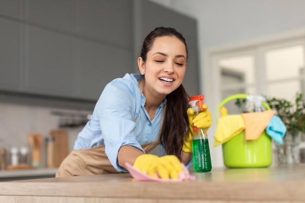 Mulher alegre a limpar a bancada da cozinha
