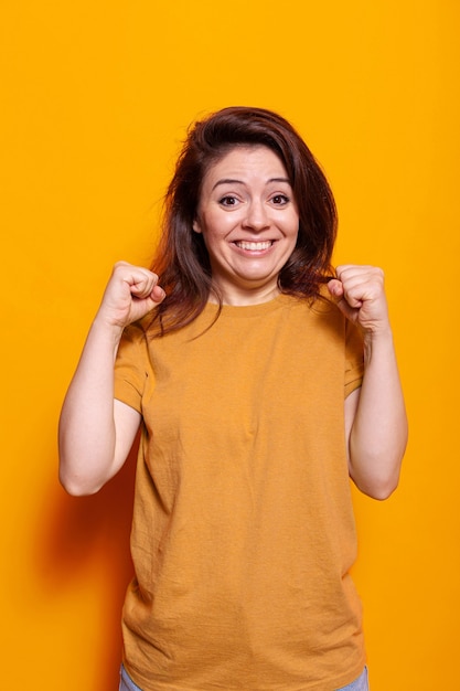 Mulher alegre cerrando os punhos e sorrindo no estúdio