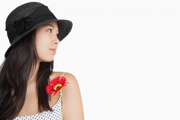 Mulher alegre com flores olhando longe vestindo um chapéu